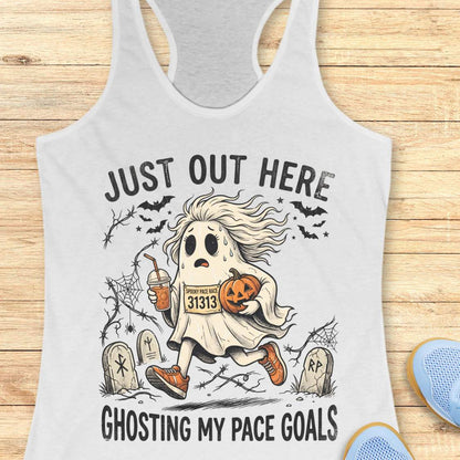 white Halloween tank top with an image of a running ghost and text 'Just out here ghosting my pace goals', on a wooden surface