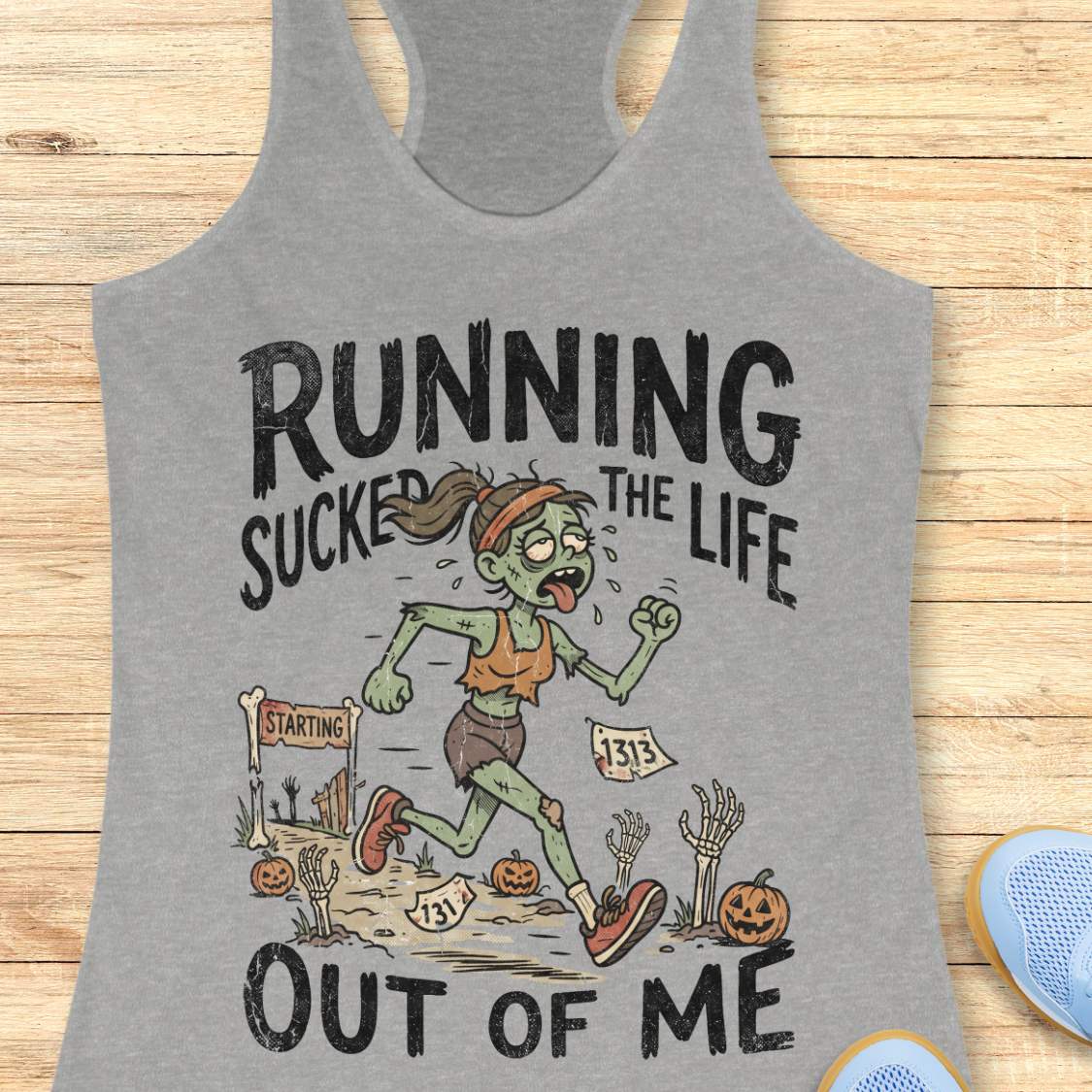 grey Halloween tank top with an image of a running zombie and text 'Running sucked the life out of me', on a wooden surface