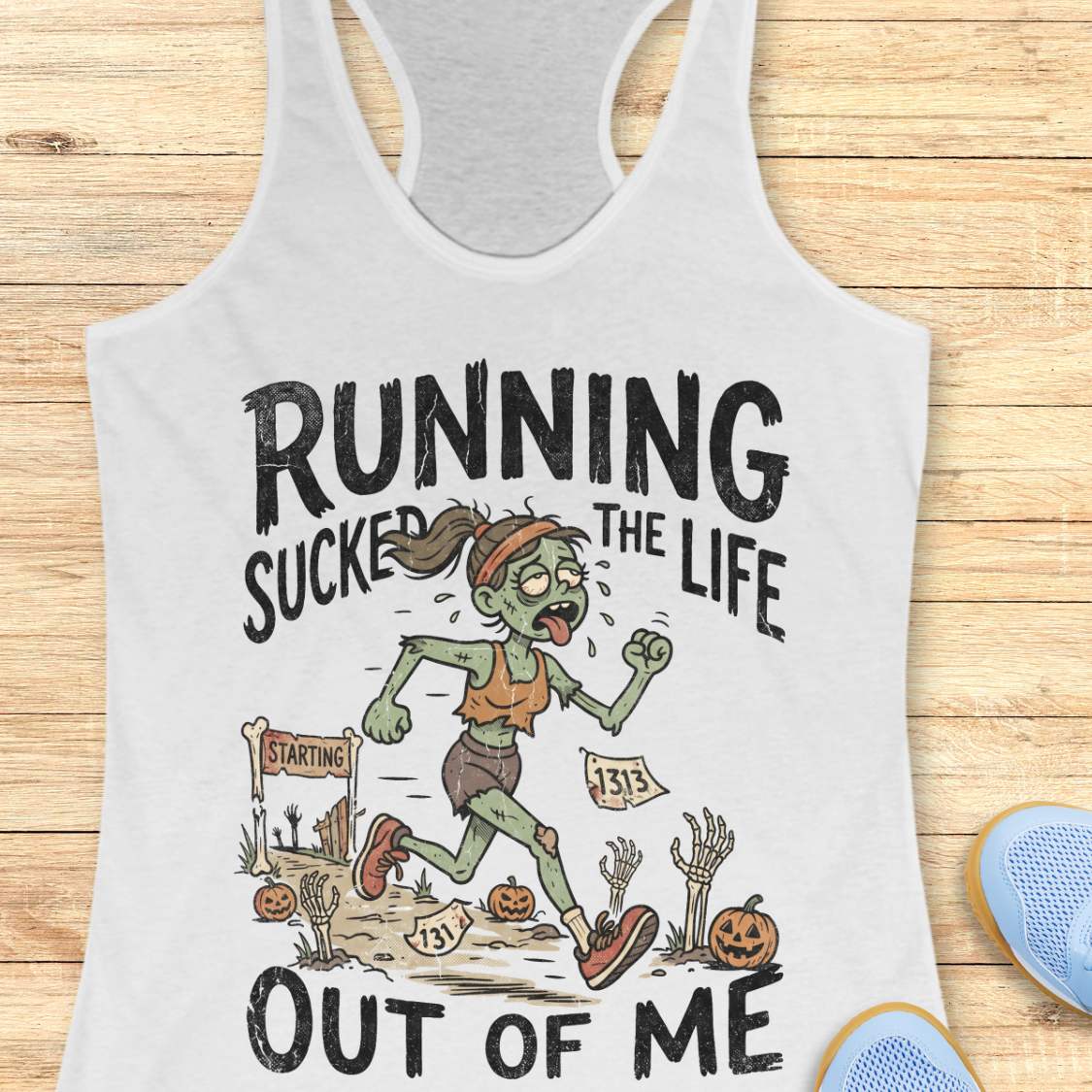 white Halloween tank top with an image of a running zombie and text 'Running sucked the life out of me', on a wooden surface
