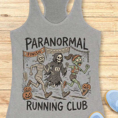 grey Halloween tank top with an image of a running zombie, mummy and reaper,  and text 'Paranormal running club', on a wooden surface