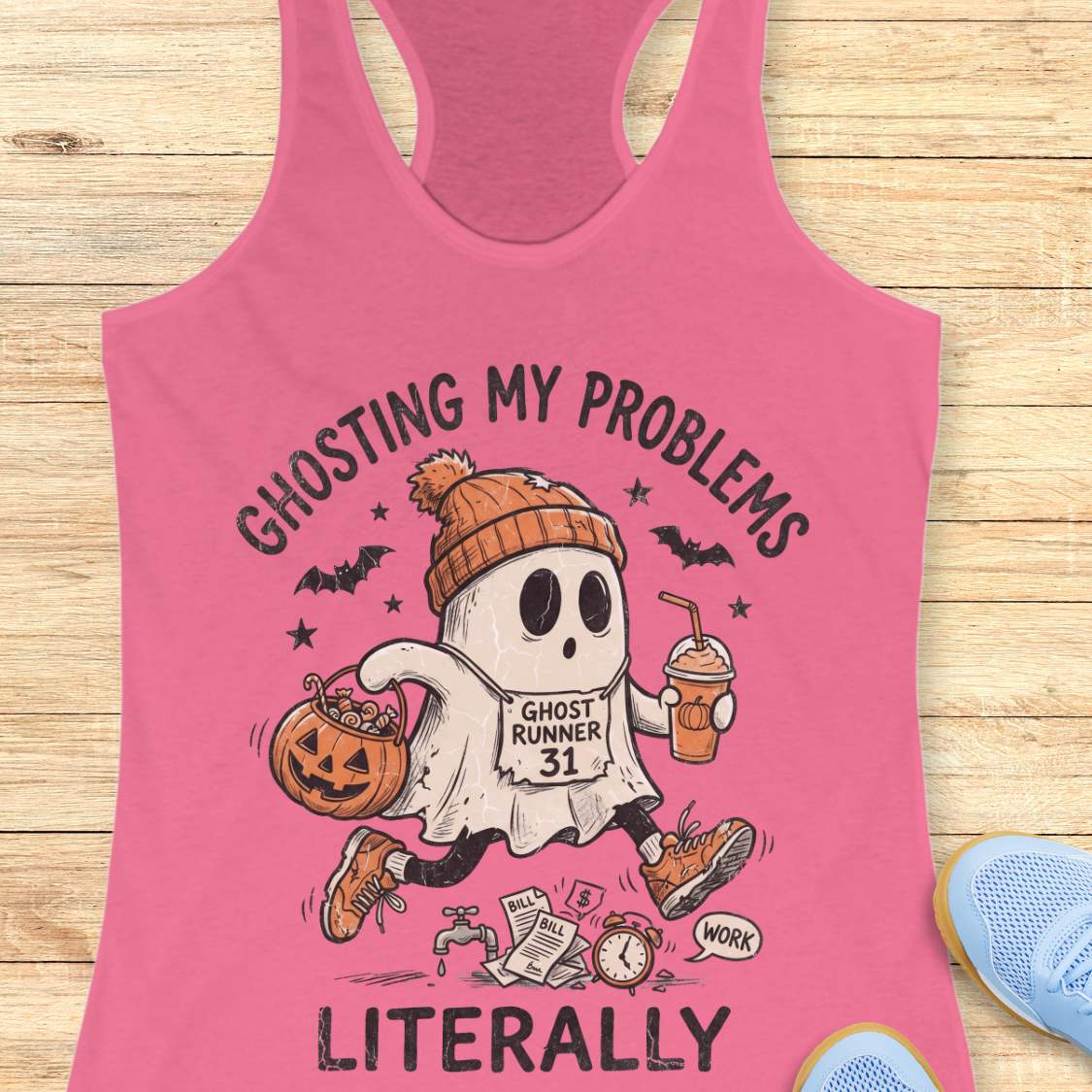 pink Halloween tank top with an image of a running ghost and text 'Ghosting my problems literally', on a wooden surface