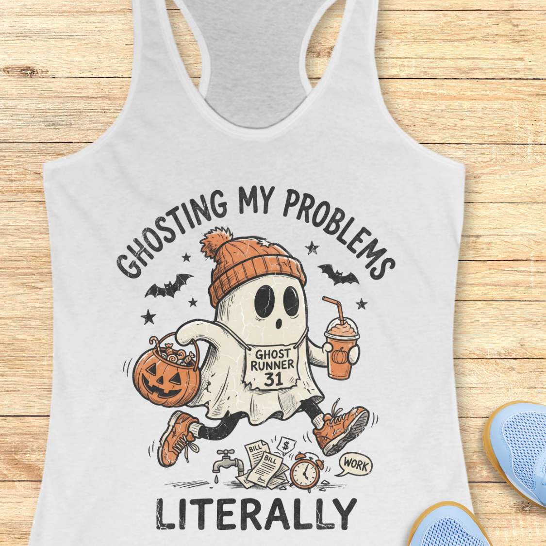 white Halloween tank top with an image of a running ghost and text 'Ghosting my problems literally', on a wooden surface