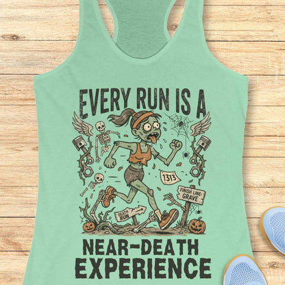 mint Halloween tank top with an image of a running zombie and text 'Every run is a near-death experience', on a wooden surface