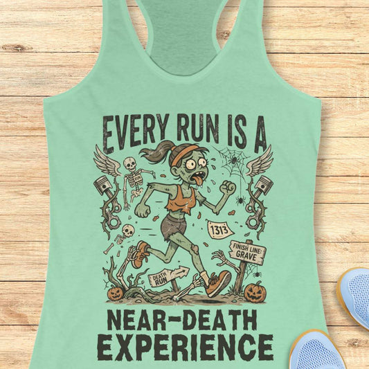mint Halloween tank top with an image of a running zombie and text 'Every run is a near-death experience', on a wooden surface
