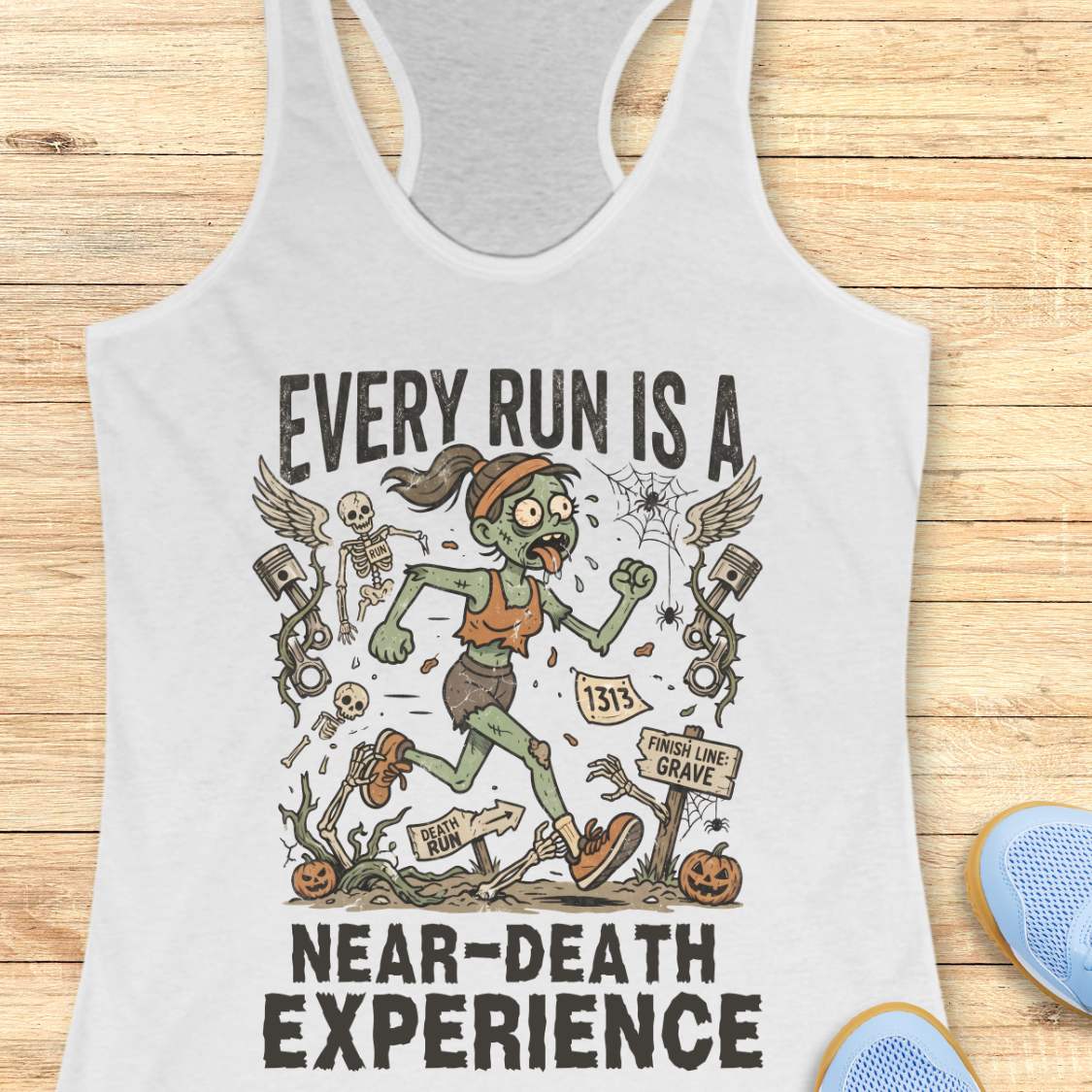 white Halloween tank top with an image of a running zombie and text 'Every run is a near-death experience', on a wooden surface