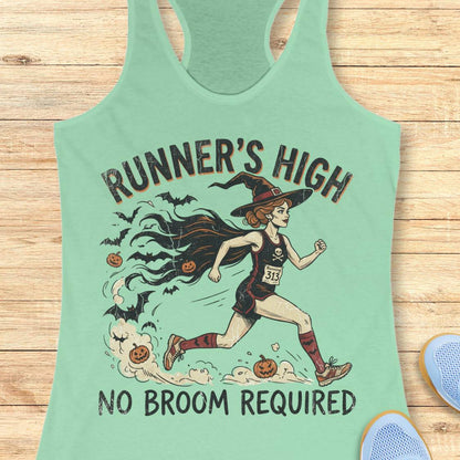 A mint green racerback tank top featuring a graphic of a witch running with pumpkins and bats, with the text 'RUNNER'S HIGH' and 'NO BROOM REQUIRED'. The tank top is displayed flat on a light wood background with partial blue shoes visible in the corners.
