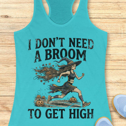 A turquoise racerback tank top laid flat on a light wood surface, featuring a large black graphic of a witch running with pumpkins and the text 'I DON'T NEED A BROOM TO GET HIGH.' A partial light blue shoe is visible at the lower right edge.