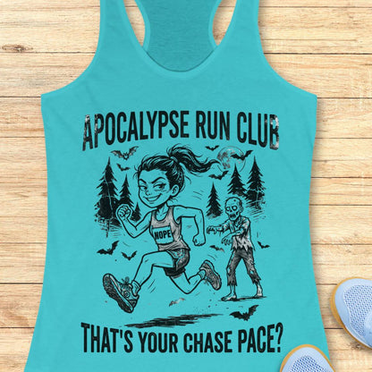 A turquoise racerback tank top laid flat on a light wood surface, featuring a black graphic of a woman running with a zombie and the text 'APOCALYPSE RUN CLUB' and 'THAT'S YOUR CHASE PACE?'. A partial sneaker appears at the bottom right.
