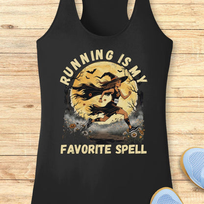 A black racerback tank top laid flat on a light wood background, featuring a distressed graphic of a female runner in front of a full moon with the text 'RUNNING IS MY FAVORITE SPELL'.