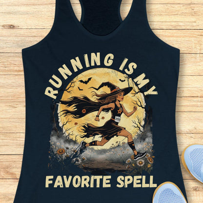 A navy blue racerback tank top laid flat on a light wood background, featuring a graphic of a woman running in front of a full moon with the text 'RUNNING IS MY FAVORITE SPELL'.