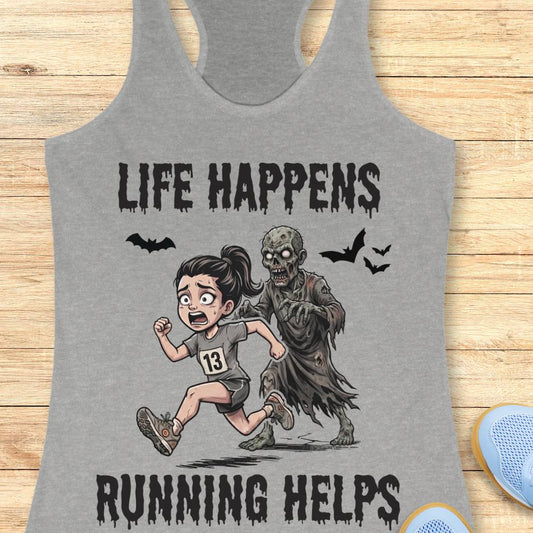 A heather gray racerback tank top laid flat on a light wood surface, featuring a Halloween graphic of a girl running with a zombie and the text 'LIFE HAPPENS RUNNING HELPS'.
