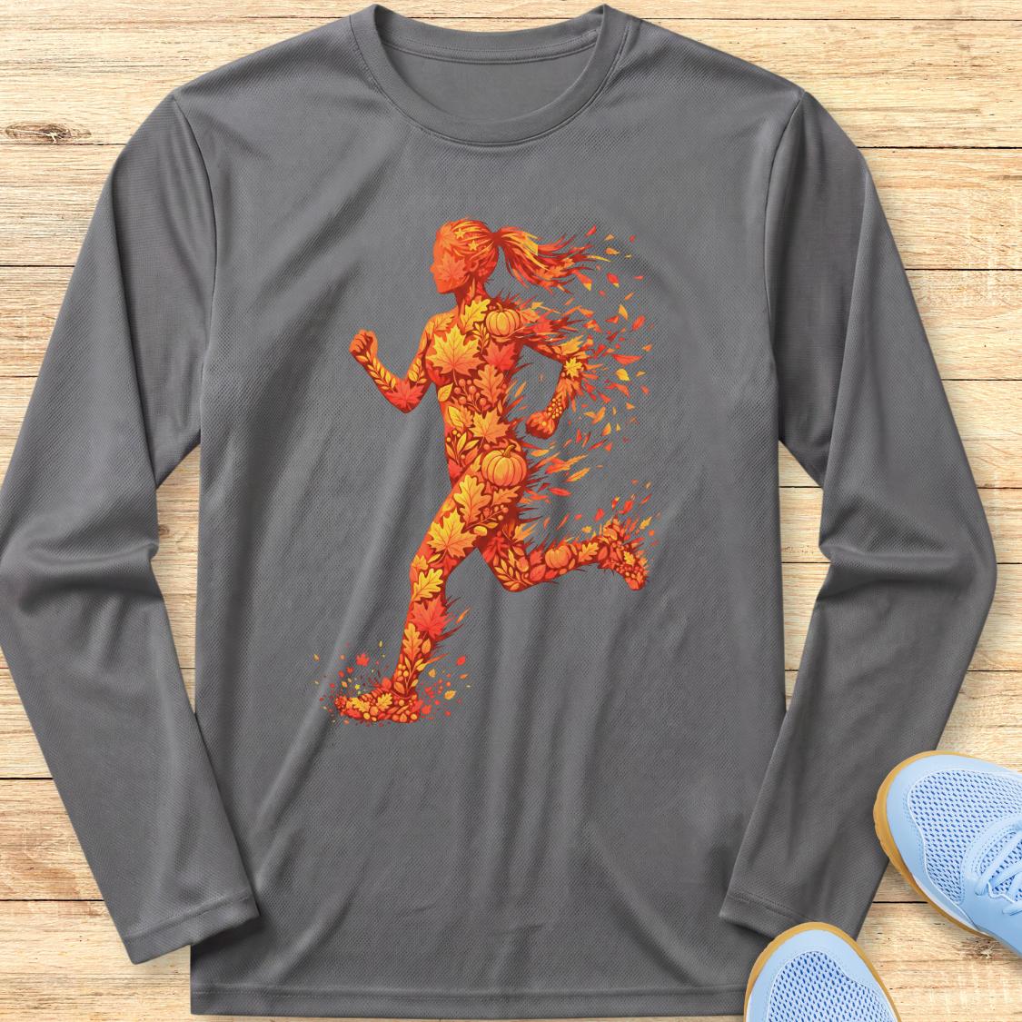 A dark gray long-sleeve athletic t-shirt with a graphic of a running woman made of orange and yellow flames, laid flat on a light wood background with blue sneakers partially visible in the corner.