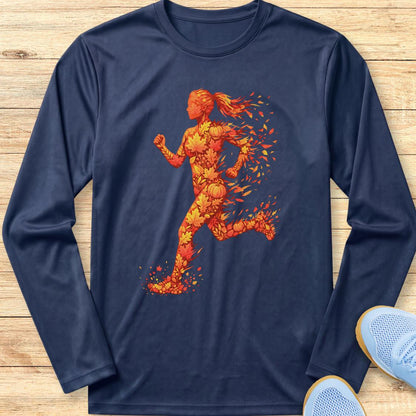 A navy blue long-sleeve t-shirt with a graphic of a female runner composed of orange and yellow soccer balls, laid flat on a light wood background with light blue sneakers partially visible in the corner.