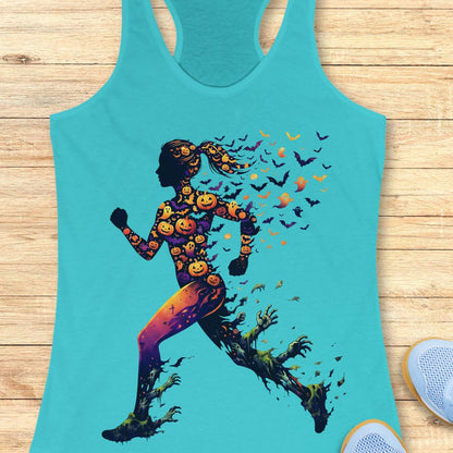 A turquoise racerback tank top laid flat on a light wood surface, featuring a large Halloween-themed graphic of a running silhouette filled with pumpkins and surrounded by bats and ghosts.