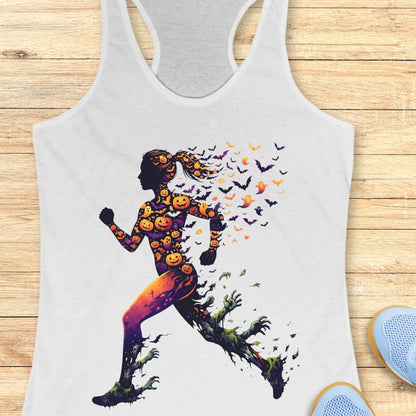 A white racerback tank top laid flat on a light wood surface, featuring a large graphic of a running silhouette filled with orange pumpkins and bats, with green vines trailing from the feet. Part of a blue shoe is visible at the bottom right.