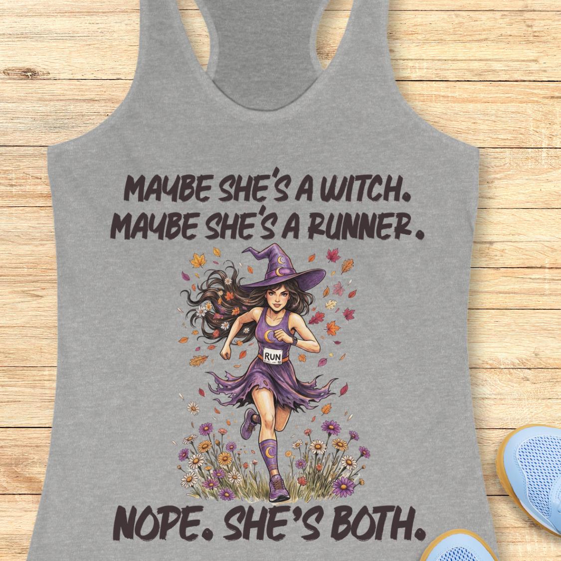 A heather gray racerback tank top laid flat on a light wood background, featuring a graphic of a witch running with the text 'MAYBE SHE'S A WITCH. MAYBE SHE'S A RUNNER.