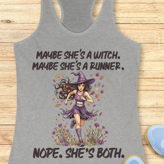 A heather gray racerback tank top laid flat on a light wood background, featuring a graphic of a witch running with the text 'MAYBE SHE'S A WITCH. MAYBE SHE'S A RUNNER.