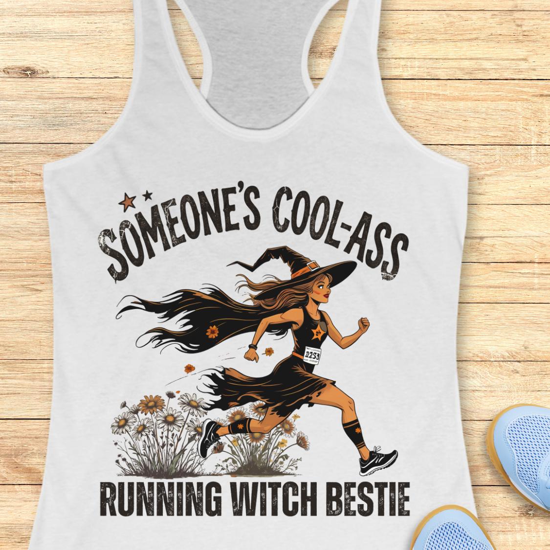 A white racerback tank top laid flat on a light wood background, featuring a graphic of a woman running as a witch with the text 'SOMEONE'S COOL-ASS RUNNING WITCH BESTIE'. Partial blue shoes are visible at the bottom right.