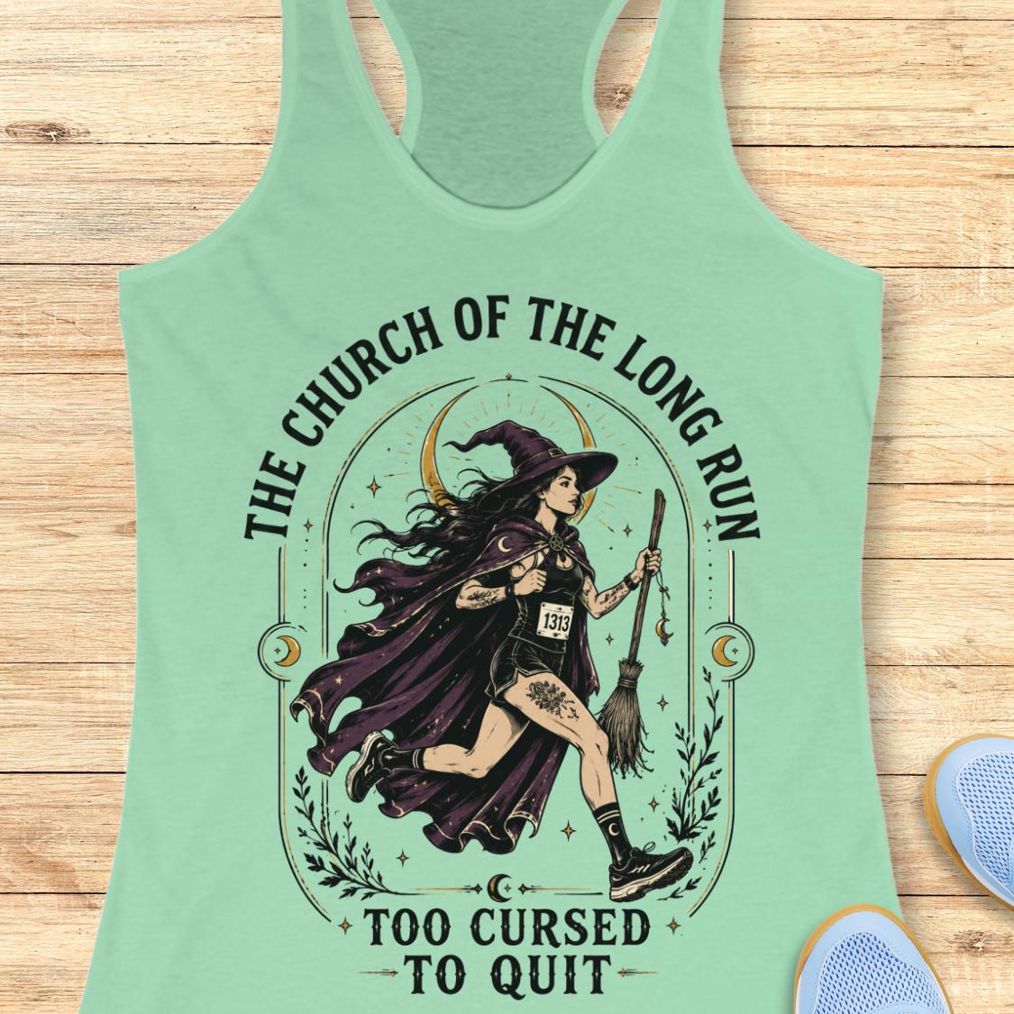 A mint green racerback tank top laid flat on a light wood background, featuring a large graphic of a witch running with a broomstick and the text 'THE CHURCH OF THE LONG RUN TOO CURSED TO QUIT'.