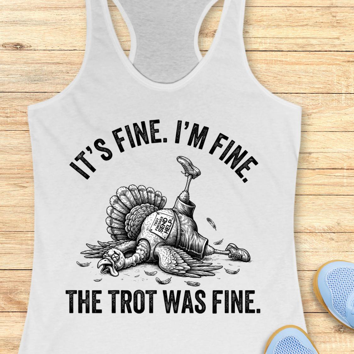 A white racerback tank top laid flat on a light wood background, featuring a black graphic of a lying turkey with one leg raised and the text 'IT'S FINE. I'M FINE.