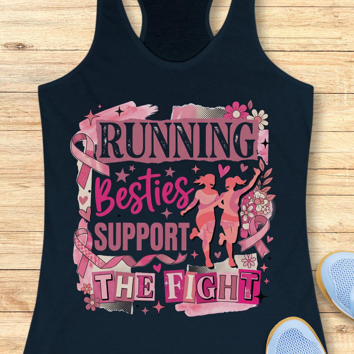 A navy racerback tank top with a pink and black graphic that reads 'running besties support the fight' in stylized lettering, surrounded by pink ribbon motifs and small runner silhouettes, shown on a wooden plank background with partial blue shoes at the edges.