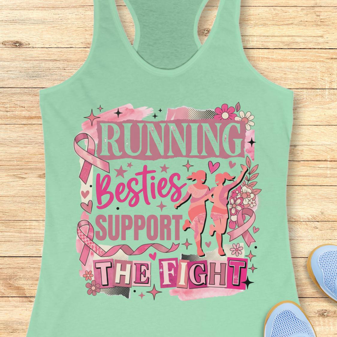 A mint racerback tank top with a pink and black graphic that reads 'running besties support the fight' in stylized lettering, surrounded by pink ribbon motifs and small runner silhouettes, shown on a wooden plank background with partial blue shoes at the edges.