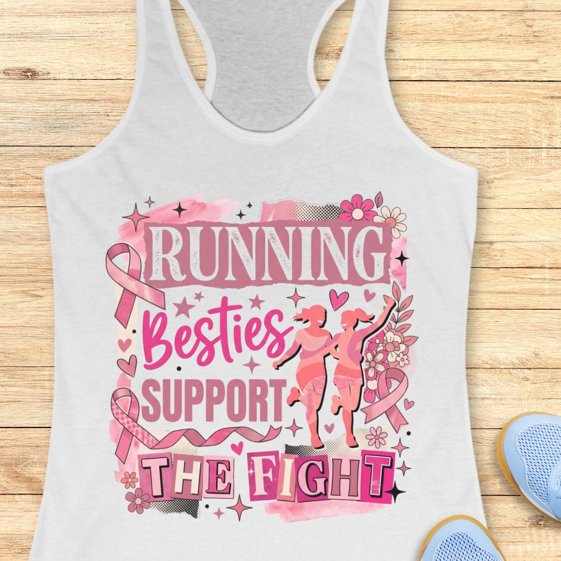 A white racerback tank top with a pink and black graphic that reads 'running besties support the fight' in stylized lettering, surrounded by pink ribbon motifs and small runner silhouettes, shown on a wooden plank background with partial blue shoes at the edges.