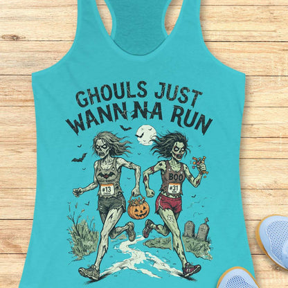 A turquoise racerback tank top laid flat on a light wood surface, featuring a Halloween graphic of two zombie runners with the text 'GHOULS JUST WANNNA RUN' and a jack-o'-lantern. Part of a blue shoe is visible at the bottom right.