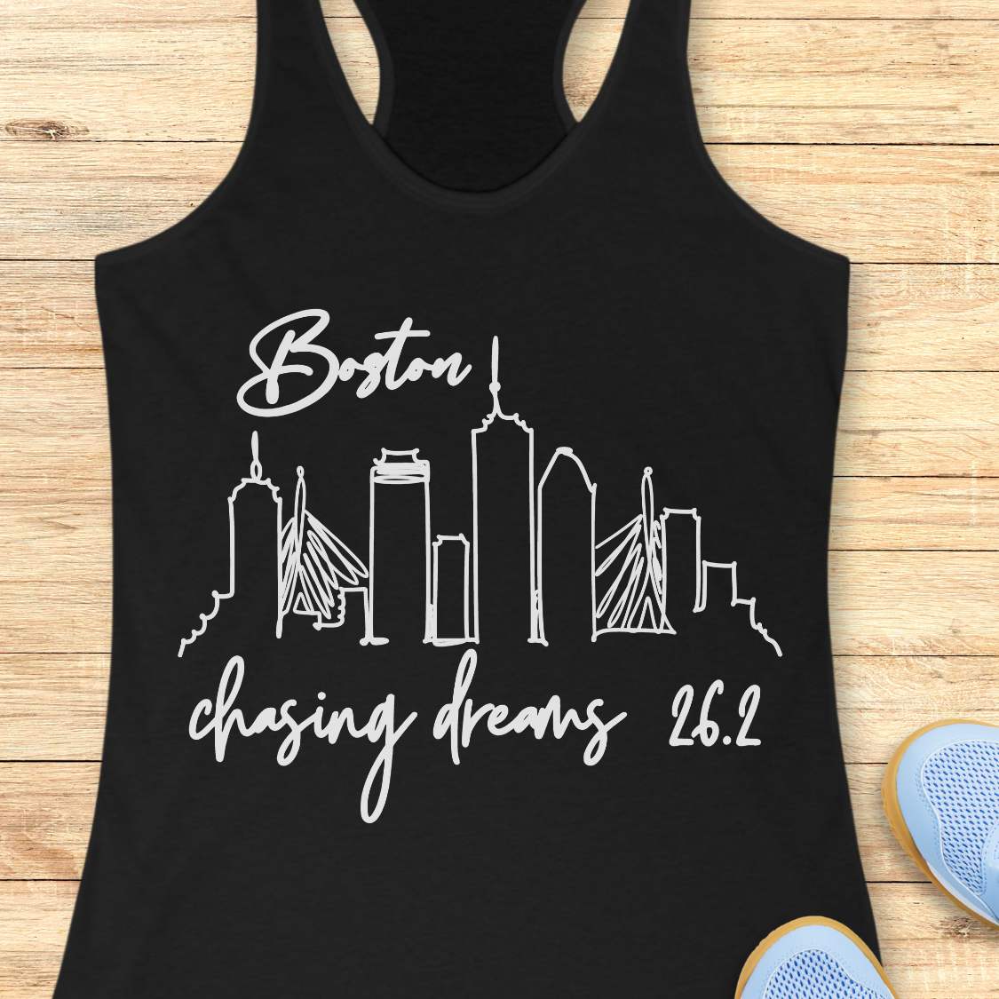 Black tank top with white 'Boston chasing dreams 26.2' design on a wooden surface