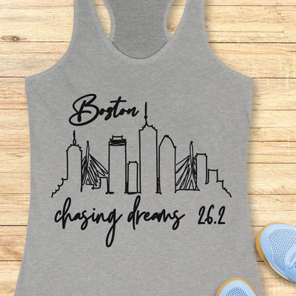 Gray tank top with black 'Boston chasing dreams 26.2' design on a wooden surface