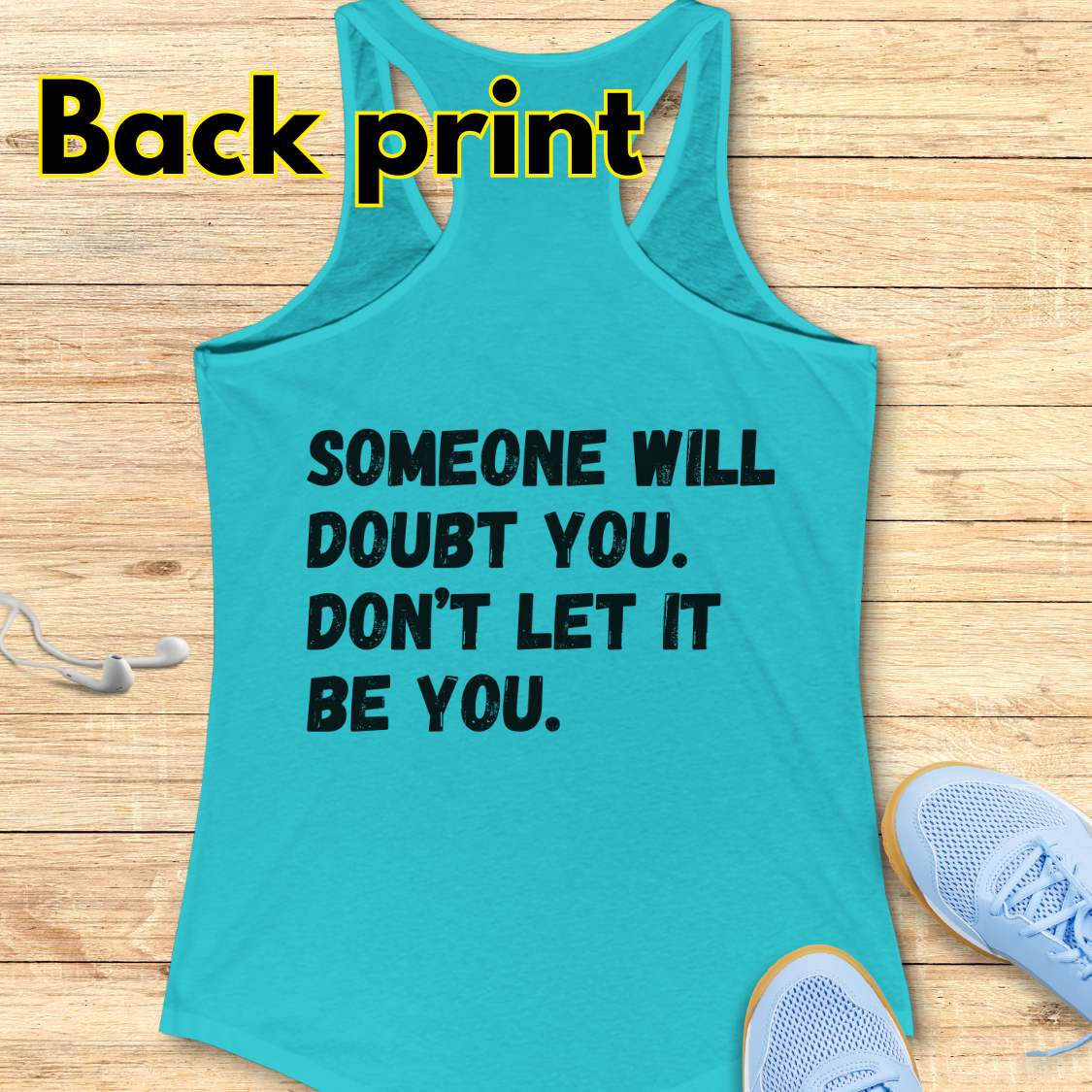 a blue tank op with a text at the back of the tank top "Someone will doubt you. Don't let it be you." on a wooden background