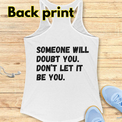 a white tank op with a text at the back of the tank top "Someone will doubt you. Don't let it be you." on a wooden background