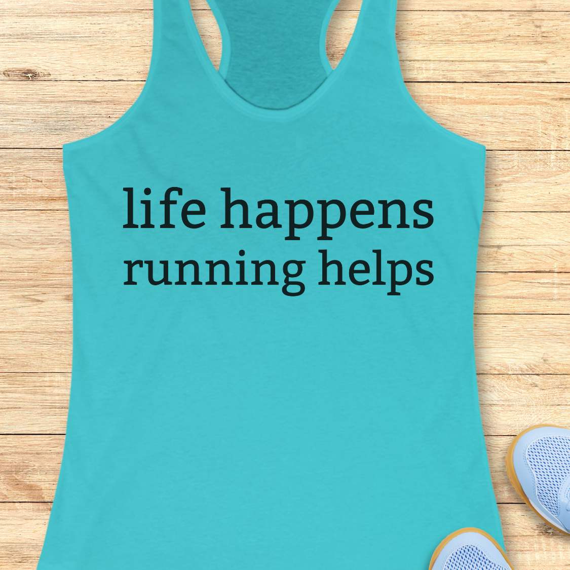 Turquoise tank top with 'life happens running helps' text on a wooden surface
