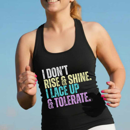 A woman running outdoors in a black tank top displaying the multi-colored slogan I DON'T RISE & SHINE I LACE UP & TOLERATE with bright pink fingernails against a clear blue sky