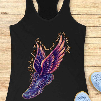 Digital graphic print on black tank top featuring a winged running shoe design with elaborate purple and blue swirling patterns, vibrant purple pink orange and yellow wings, and text reading she has fire in her soul and wings on her feet surrounding it