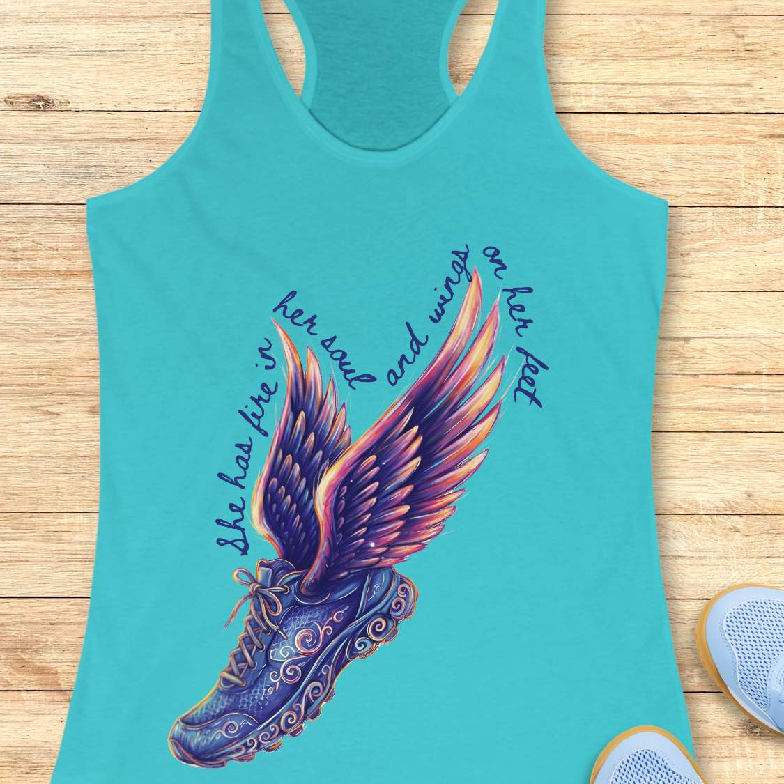 Turquoise tank top with Digital graphic print featuring a winged running shoe design with elaborate purple and blue swirling patterns, vibrant purple pink orange and yellow wings, and text reading she has fire in her soul and wings on her feet surrounding it