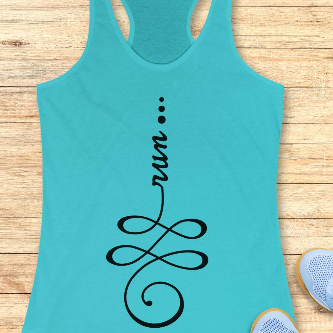 A turquoise racerback tank top with a black graphic print reading 'run' above an infinity symbol, laid flat on a light wood plank background with partial sneakers visible at the edges.