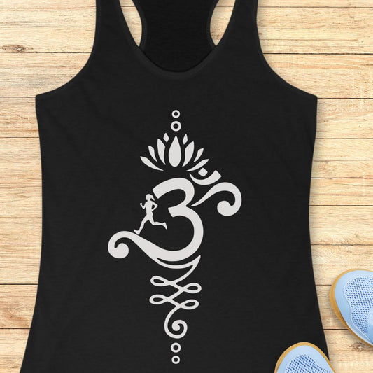 A black racerback tank top with a large white Om symbol and lotus design printed on the front, displayed flat on a light wood background with blue sneakers partially visible at the bottom right.