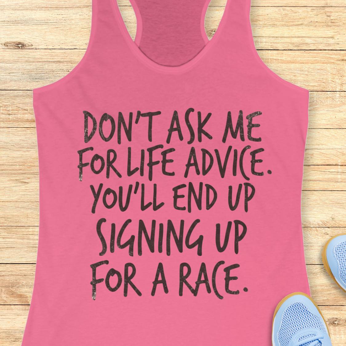 A pink racerback tank top with black hand-drawn text reading 'DON'T ASK ME FOR LIFE ADVICE. YOU'LL END UP SIGNING UP FOR A RACE.