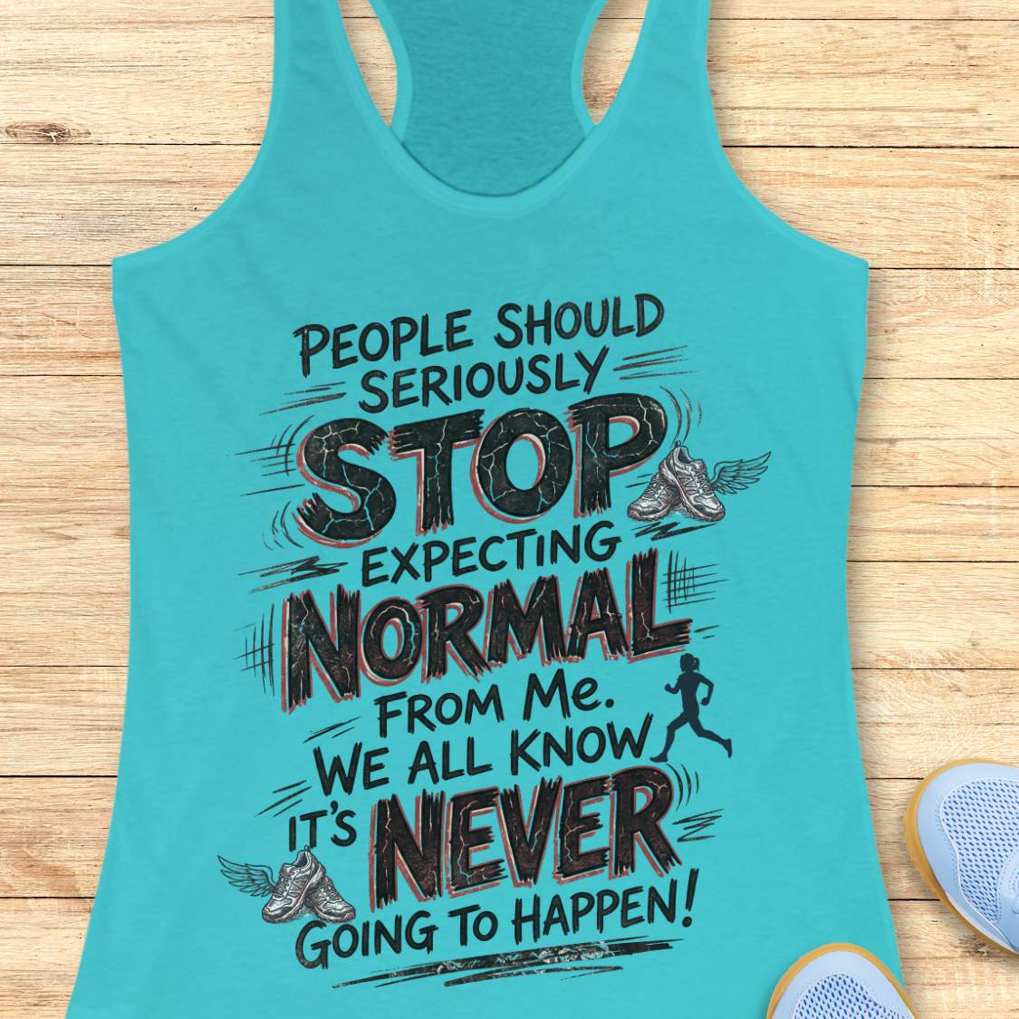 A turquoise racerback tank top with a humorous running-themed graphic, displayed flat on a light wood background with partial shoes visible at the edges.