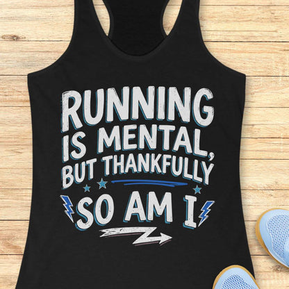 A black racerback tank top laid flat on a light wood background, featuring a distressed white graphic with blue shadowing that reads, 'RUNNING IS MENTAL, BUT THANKFULLY SO AM I.' Partial blue sneakers are visible at the bottom right as styling props.
