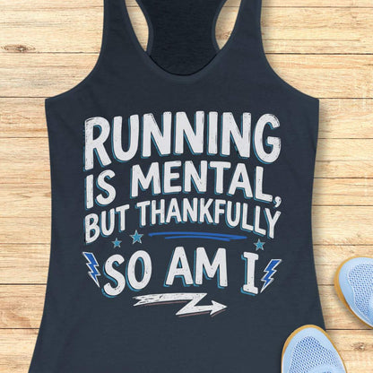 A indigo racerback tank top with a motivational graphic reading 'RUNNING IS MENTAL, BUT THANKFULLY SO AM I' in white and light blue, laid flat on a light wood plank background with partial sneakers visible at the edges.