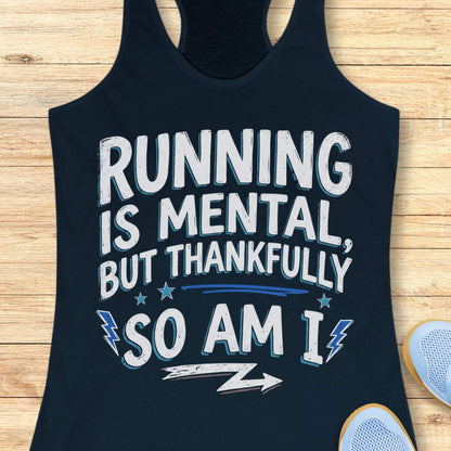A dark navy blue racerback tank top with a distressed white and blue graphic that reads 'RUNNING IS MENTAL, BUT THANKFULLY SO AM I' laid flat on a light wood background, with partial sneakers visible at the edges.