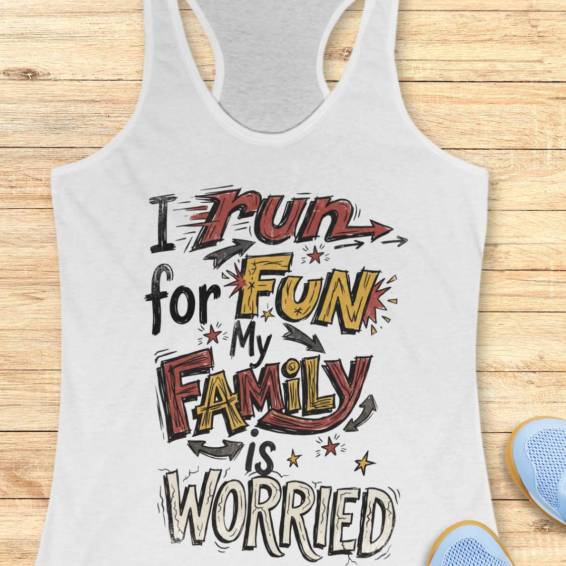 A white racerback tank top with a colorful graphic text that reads 'I run for FUN My FAMILY is WORRIED' in red, yellow, and black stylized lettering, displayed flat on a light wood background with partial blue shoes visible at the bottom right.