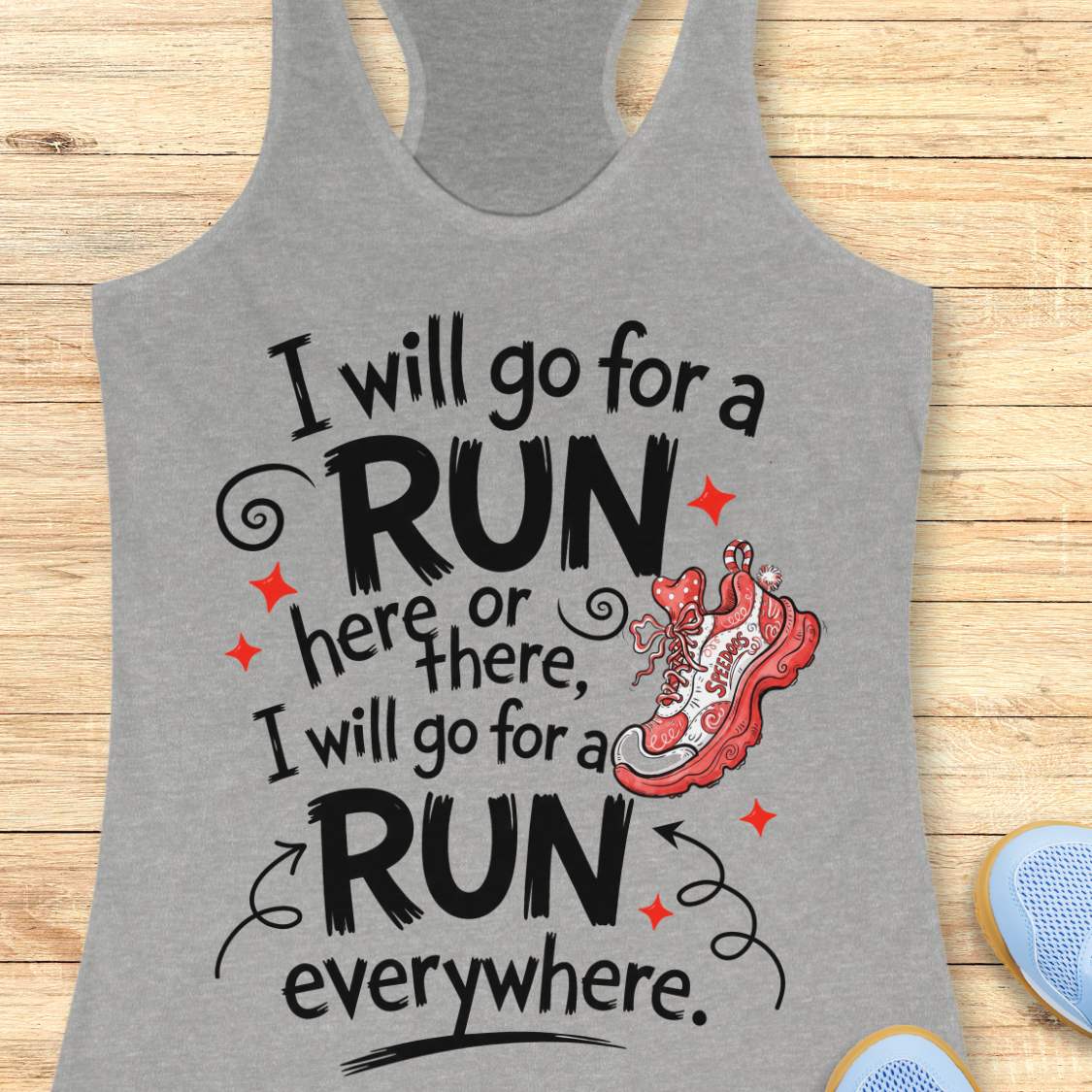 A grey racerback tank top laid flat on a light wood plank background, featuring a graphic print that reads 'I will go for a run here or there, I will go for a run everywhere.' with an illustrated of a red running shoe.