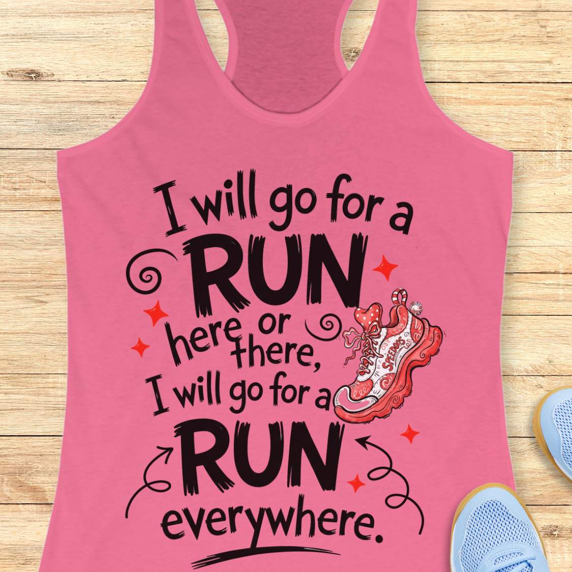 A pink racerback tank top laid flat on a light wood background, featuring a motivational quote in black and white text that reads 'I will go for a RUN here or there, I will go for a RUN everywhere.' with a red and white running shoe illustration and small red star accents.