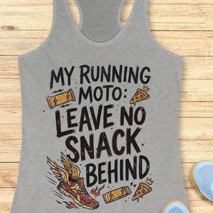 A heather gray racerback tank top with a graphic print that reads 'MY RUNNING MOTO: LEAVE NO SNACK BEHIND' in black distressed lettering, decorated with illustrations of a winged running shoe, pizza slices, and energy bars. The tank top is laid flat on a light wood plank background.