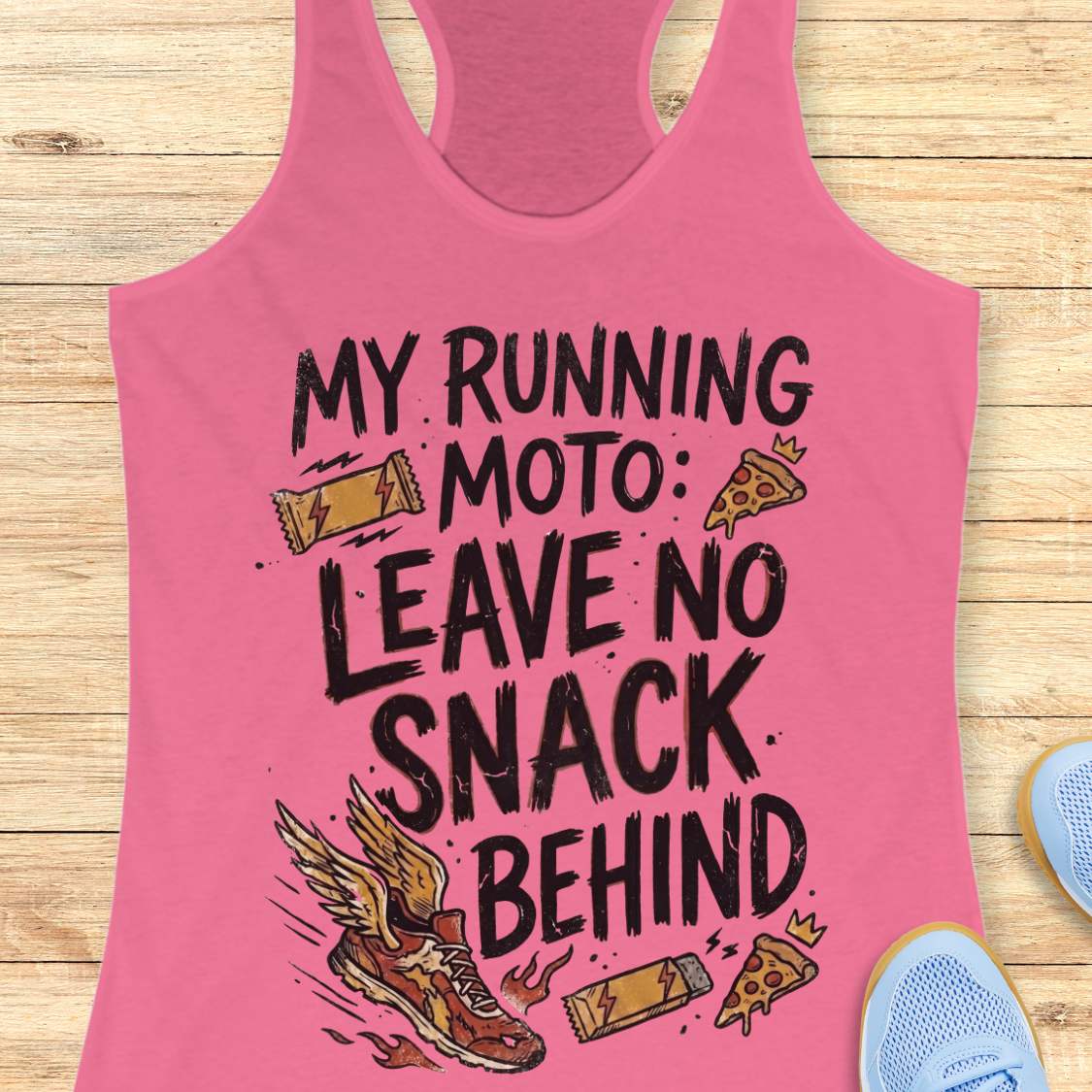 A pink racerback tank top laid flat on a light wood background, featuring a black hand-drawn style graphic that reads 'MY RUNNING MOTO: LEAVE NO SNACK BEHIND' with illustrations of a winged running shoe, a slice of pizza, a lightning-bolt snack bar, and a small crown.