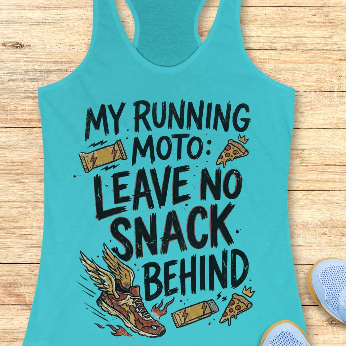 A turquoise racerback tank top laid flat on a light wood surface, featuring a humorous graphic that reads 'MY RUNNING MOTO: LEAVE NO SNACK BEHIND' with illustrations of a winged running shoe, candy bars, and pizza slices. Partial light blue sneakers are visible at the bottom right corners.