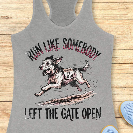 A heather gray racerback tank top laid flat on a light wood background, featuring a graphic of a dog wearing a race bib and the text 'RUN LIKE SOMEBODY LEFT THE GATE OPEN'.